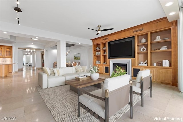 living room with visible vents, built in shelves, ceiling fan with notable chandelier, a fireplace, and light tile patterned flooring