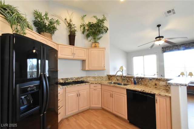 kitchen with visible vents, a peninsula, light brown cabinetry, a sink, and black appliances