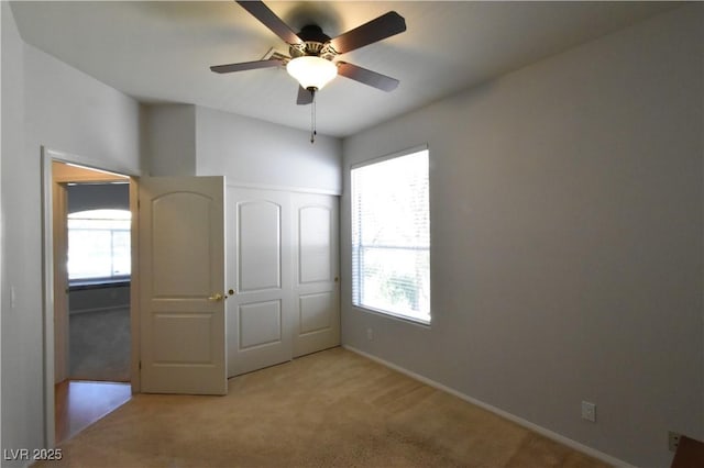 unfurnished bedroom with multiple windows, carpet floors, baseboards, and a ceiling fan