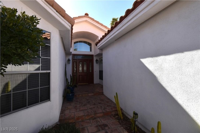 doorway to property with a tile roof and stucco siding