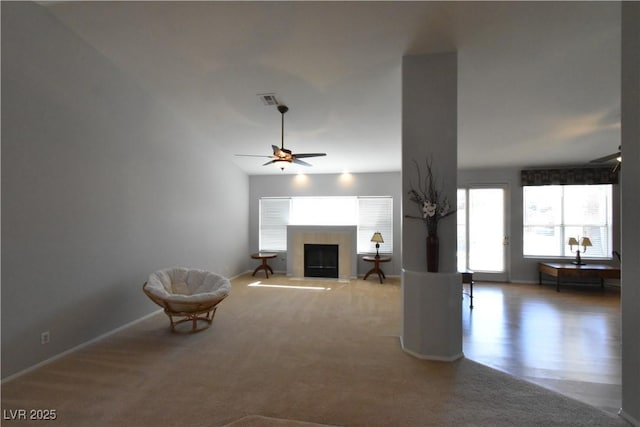 unfurnished living room featuring a fireplace with flush hearth, a ceiling fan, baseboards, and carpet floors