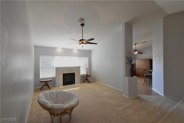 living area featuring light colored carpet, a fireplace, a ceiling fan, and vaulted ceiling