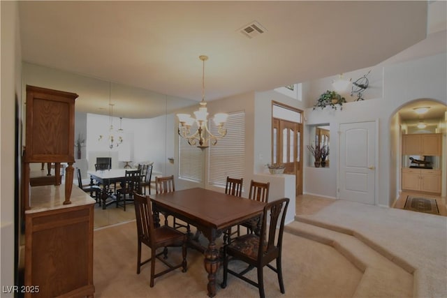 dining room featuring arched walkways, visible vents, light colored carpet, and an inviting chandelier