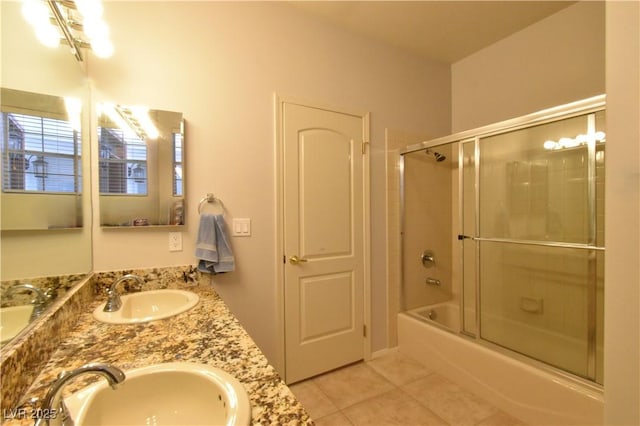 bathroom with tile patterned flooring, combined bath / shower with glass door, double vanity, and a sink