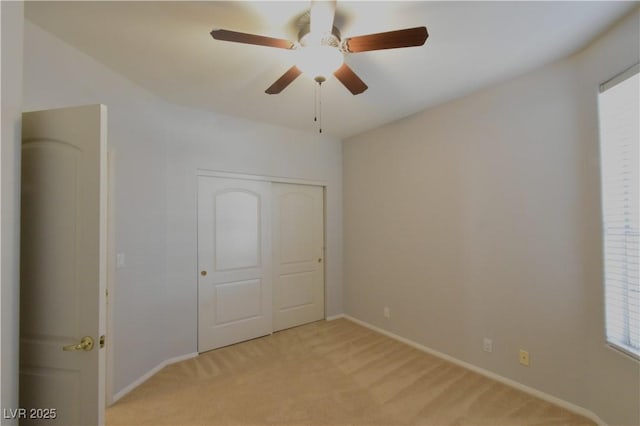 unfurnished bedroom featuring a closet, light colored carpet, baseboards, and ceiling fan