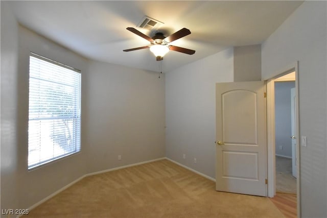 empty room with visible vents, light carpet, baseboards, and a ceiling fan