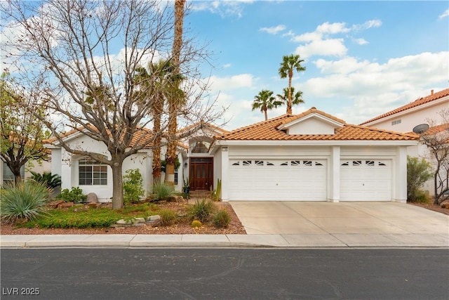 mediterranean / spanish house with a garage, concrete driveway, stucco siding, and a tile roof