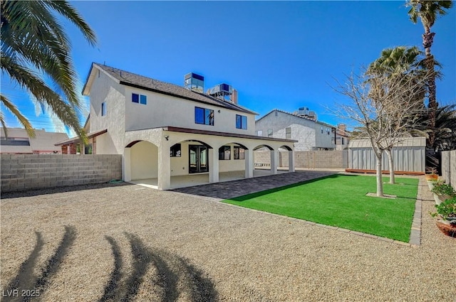 rear view of property with a lawn, cooling unit, stucco siding, a fenced backyard, and an outbuilding