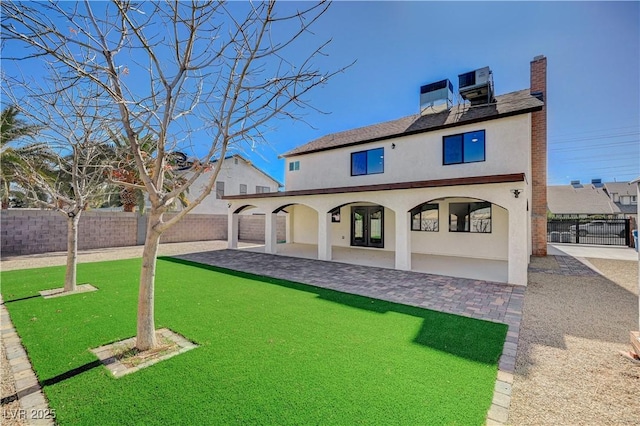 rear view of house featuring stucco siding, a patio, and a fenced backyard