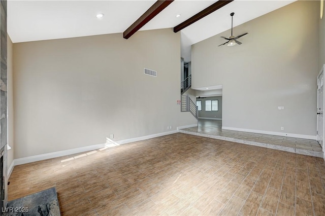 unfurnished living room with visible vents, beamed ceiling, a ceiling fan, wood finished floors, and stairs