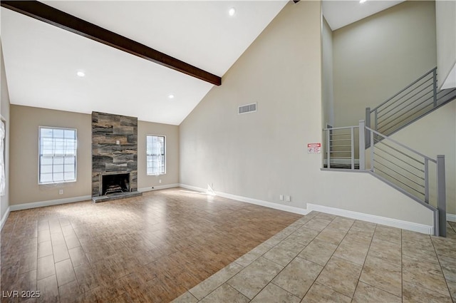 unfurnished living room with visible vents, stairs, beam ceiling, a fireplace, and wood finished floors