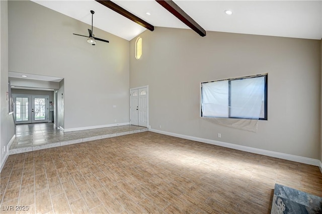 unfurnished living room with beam ceiling, baseboards, and wood finished floors