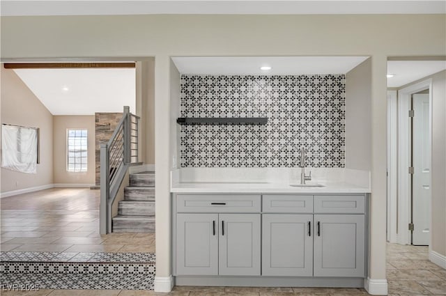 bar featuring indoor wet bar, stairway, baseboards, and a sink