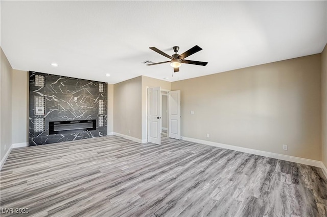 unfurnished living room with a ceiling fan, wood finished floors, a fireplace, and baseboards