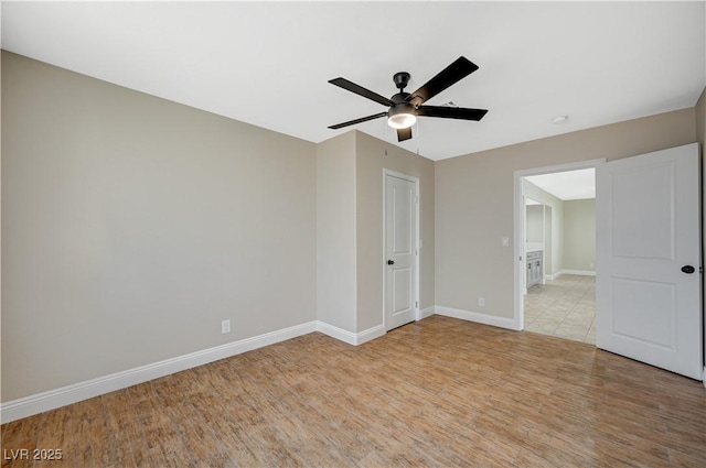 empty room featuring light wood finished floors, ceiling fan, and baseboards