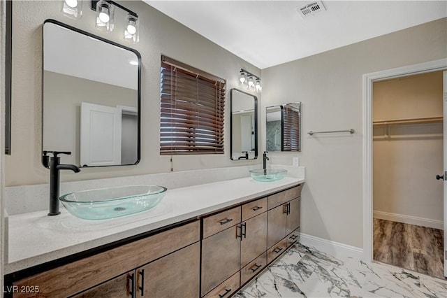 full bath featuring double vanity, visible vents, marble finish floor, and a sink