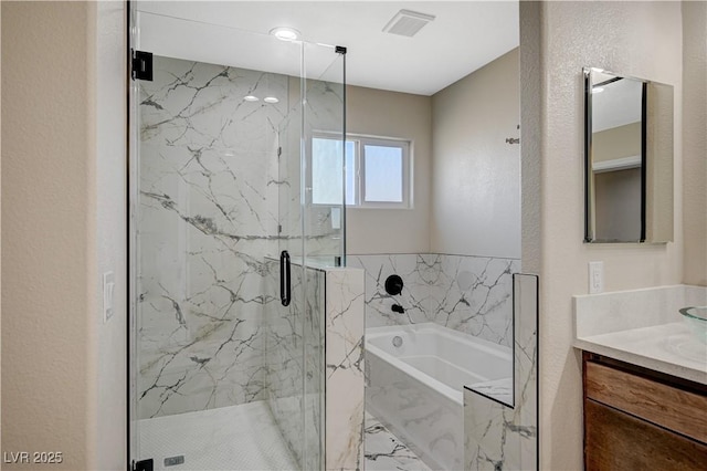 bathroom featuring vanity, a garden tub, a textured wall, and a marble finish shower