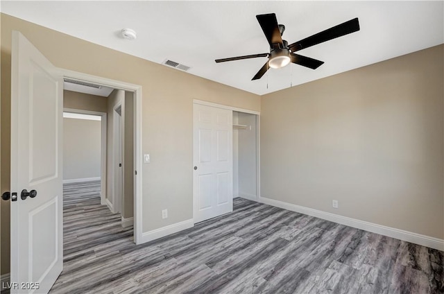 unfurnished bedroom featuring visible vents, a ceiling fan, wood finished floors, a closet, and baseboards