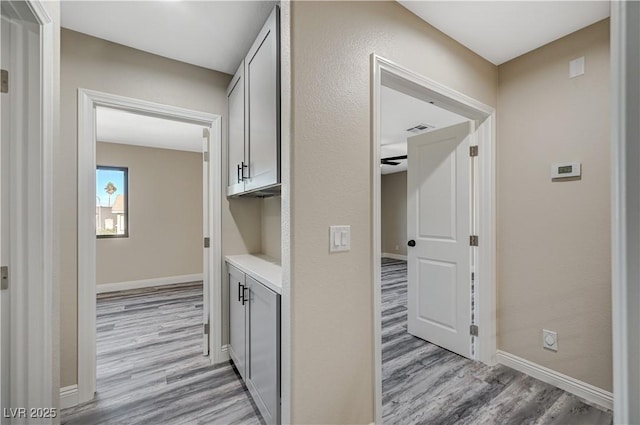 corridor with visible vents, baseboards, and light wood-type flooring