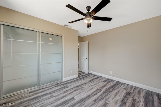 unfurnished bedroom with visible vents, wood finished floors, a closet, baseboards, and ceiling fan