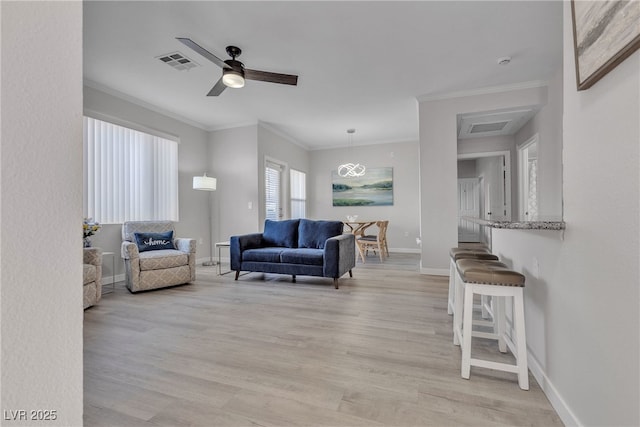 living room with crown molding, light wood-style flooring, baseboards, and visible vents