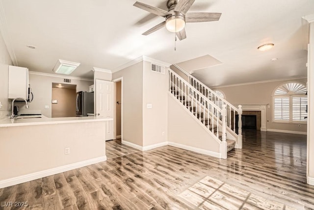 unfurnished living room with stairway, visible vents, light wood finished floors, and a sink