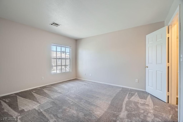 spare room featuring carpet, visible vents, and baseboards