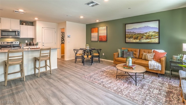 living area featuring recessed lighting, baseboards, visible vents, and light wood finished floors