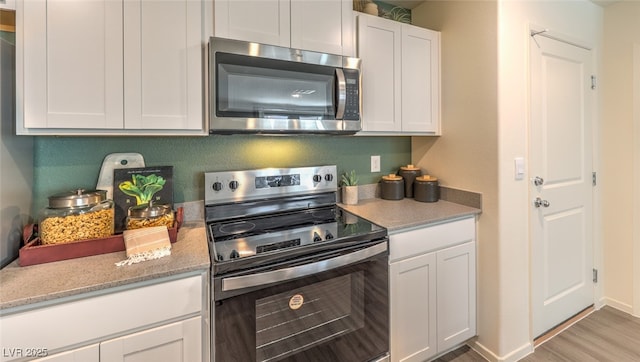 kitchen with stainless steel appliances, baseboards, light wood-style floors, white cabinets, and light stone countertops