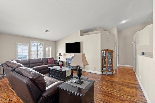 living room featuring visible vents, baseboards, lofted ceiling, and wood finished floors