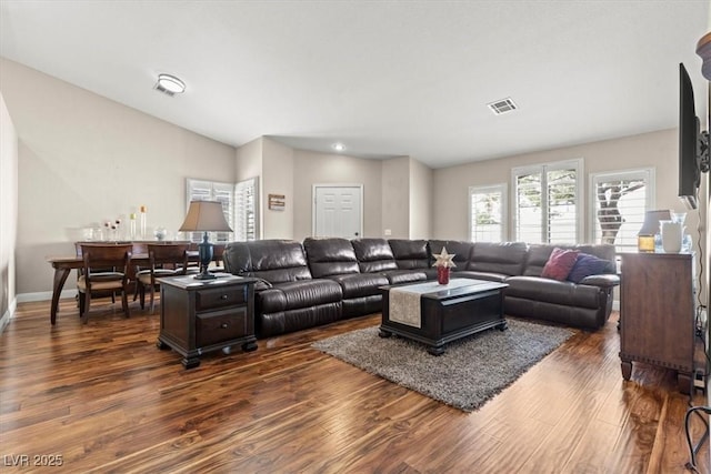 living room featuring visible vents, baseboards, and dark wood-style flooring