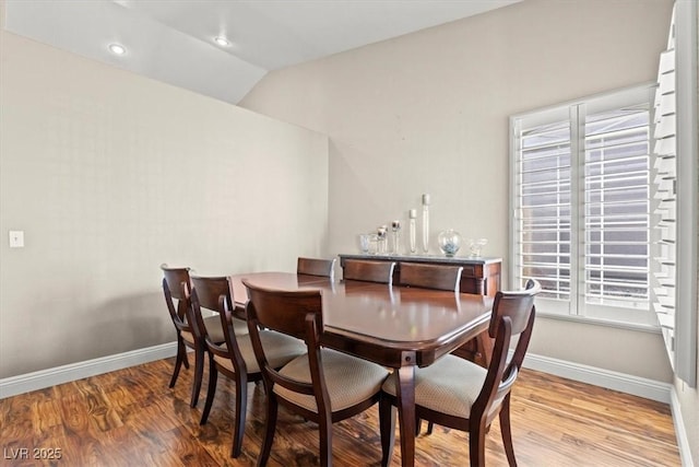 dining space featuring lofted ceiling, baseboards, and wood finished floors