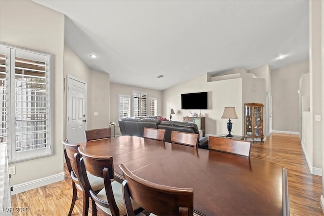 dining room featuring vaulted ceiling, baseboards, and wood finished floors