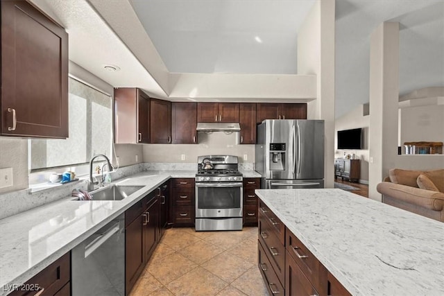 kitchen featuring under cabinet range hood, light stone counters, appliances with stainless steel finishes, and a sink