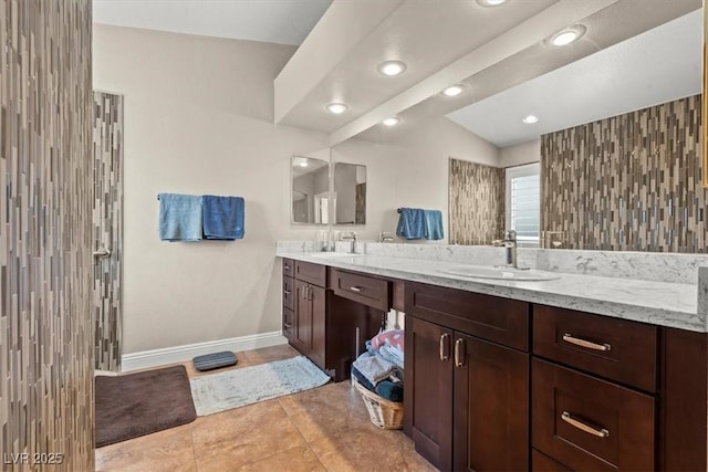 full bathroom with double vanity, baseboards, tile patterned floors, and a sink