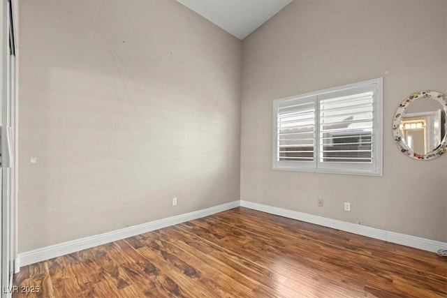 unfurnished room featuring baseboards, lofted ceiling, and wood finished floors