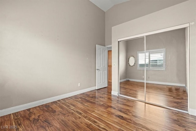 unfurnished bedroom featuring wood finished floors, baseboards, and a closet