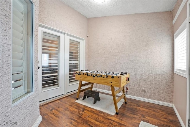 game room with baseboards, a textured ceiling, and wood finished floors