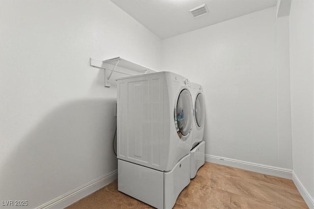 clothes washing area featuring washer and dryer, visible vents, baseboards, and laundry area