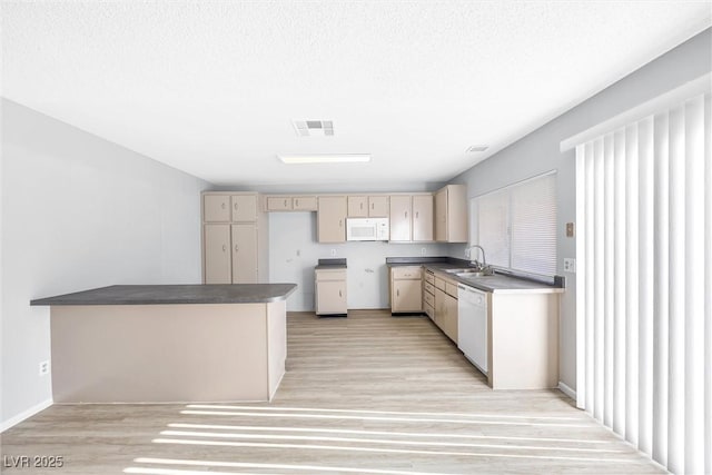 kitchen with visible vents, a sink, cream cabinets, white appliances, and light wood-style floors