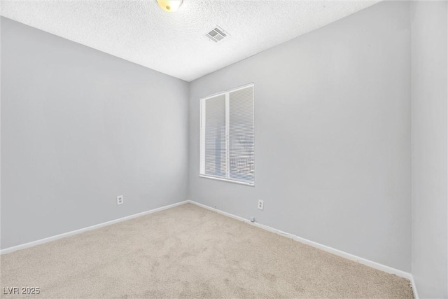 spare room featuring carpet flooring, baseboards, visible vents, and a textured ceiling