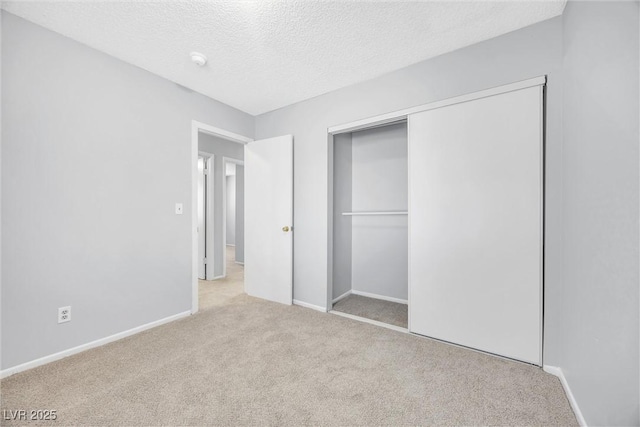 unfurnished bedroom featuring a closet, baseboards, carpet, and a textured ceiling