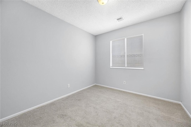 carpeted spare room featuring visible vents, baseboards, and a textured ceiling