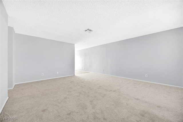 carpeted spare room with baseboards, visible vents, and a textured ceiling