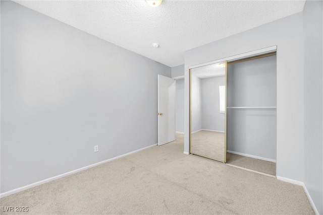 unfurnished bedroom featuring carpet flooring, baseboards, a closet, and a textured ceiling