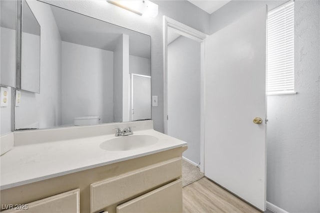 bathroom with vanity, toilet, and wood finished floors