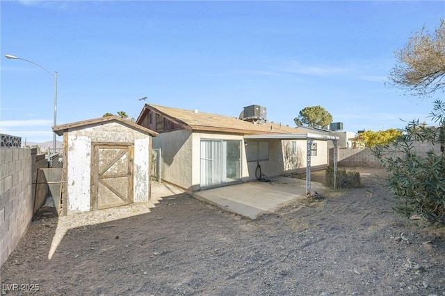 back of house featuring a patio, central AC unit, a fenced backyard, an outdoor structure, and a storage shed