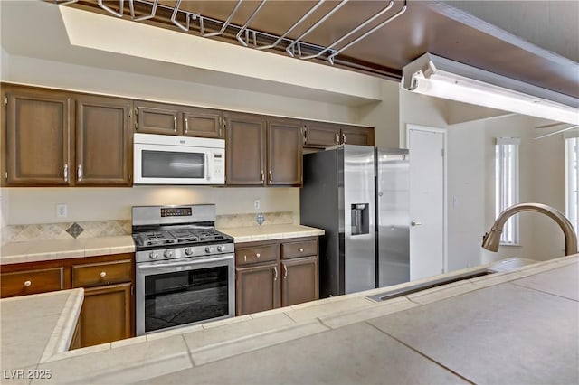 kitchen featuring tile countertops, appliances with stainless steel finishes, and a sink