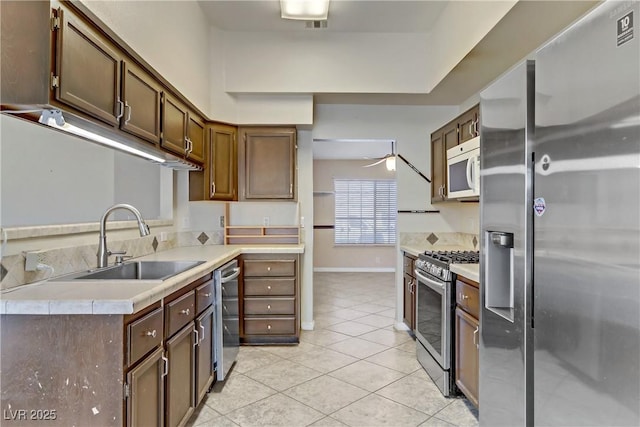 kitchen with light tile patterned floors, a ceiling fan, a sink, light countertops, and appliances with stainless steel finishes