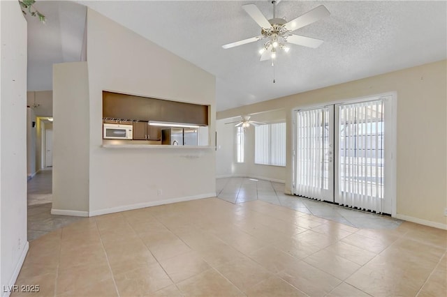 unfurnished living room featuring a textured ceiling, light tile patterned flooring, baseboards, and ceiling fan